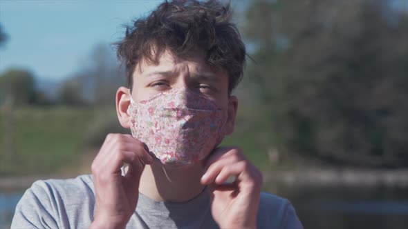 Young man puts on homemade flower pattern corona virus cotton mask CLOSE UP