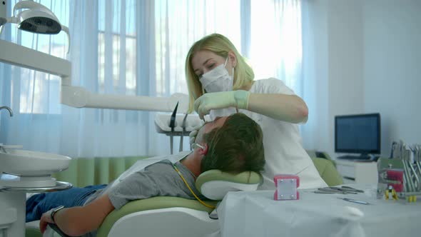 Dentist in Mask Checks the Patients Teeth