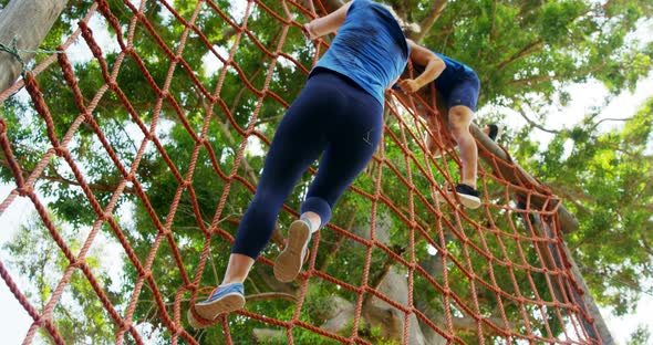 Fit people climbing a net during obstacle course 4k