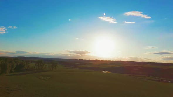 Aerial Video Flying Over Green Grass Field During Sunset in Spring Time
