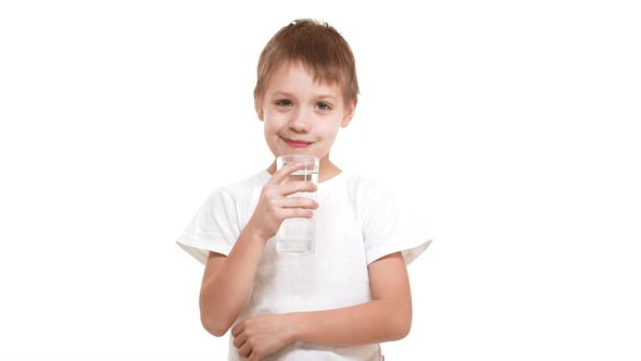 Young Blushful Caucasian Boy Drinking Clear Water From Glass and Showing Ok Standing on White