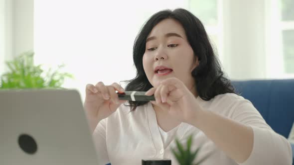 plus size Asian woman bloggers sitting are online to review cosmetic products via social media.