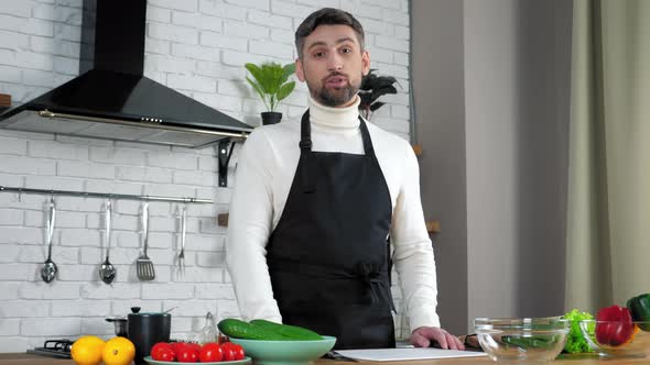 Man chef food blogger in apron greets teaches online videocall webcam in kitchen