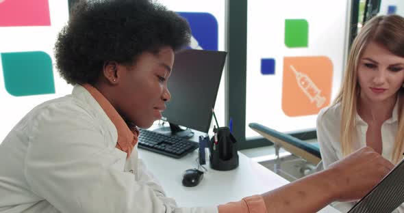 AfricanAmerican Female Doctor at the Table in the Clinic Shows the Results 