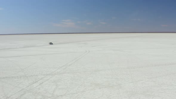 Isolated View Of A Car Traveling On Vast Salt Pans Near Kubu Island In Botswana. Aerial Drone