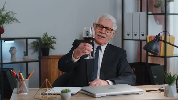 Senior Man Freelancer Drinking Wine After Working on Laptop Computer Pc Sitting at Desk at Office