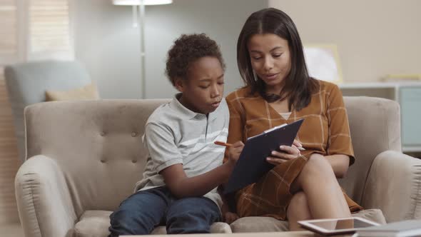 Mom Watching Son Filling in Paper