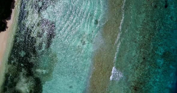 Wide overhead abstract shot of a white paradise beach and blue water background in colorful 4K