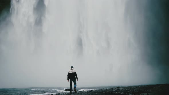 Young Traveling Man Walking Near the Powerful Gljufrabui Waterfall in Iceland and Raising Hands Up