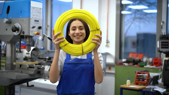 Smiling apprentice looking through yellow role of cables in factory