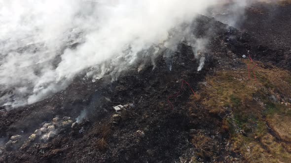 People spray water toward burning site with fire hose