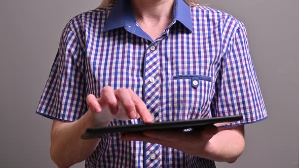 A young woman at a remote work swiping pages on a tablet screen