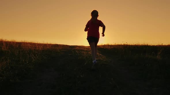 Carefree Girl Runs Up the Hill on a Sunset Background