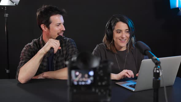 Happy male and female bloggers recording video on camera in studio