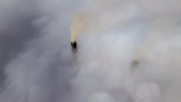 Coal Power Plant High Pipes with Black Smoke Moving Upwards Over Clouds Polluting Atmosphere