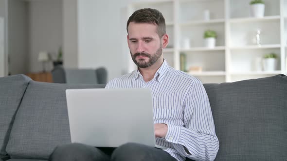 Focused Young Man Working on Laptop at Home 