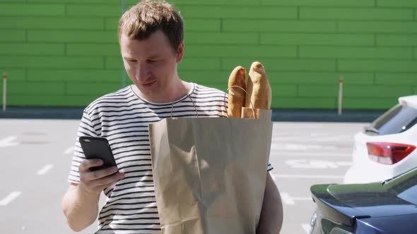 Male with Purchases Messaging After Left Grocery Store