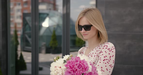 Pretty Blonde Woman Holding a Bunch of Peonies