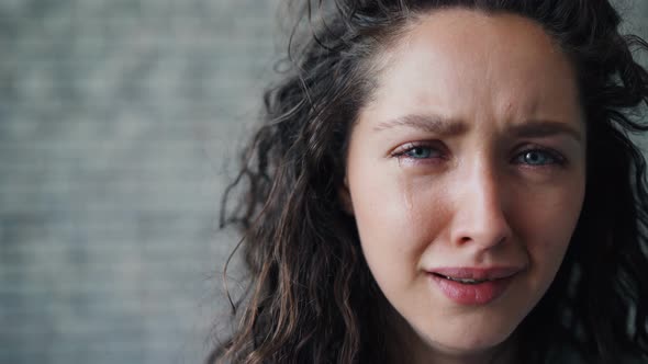 Close-up Portrait of Unhappy Young Girl Crying on Brick Wall Background