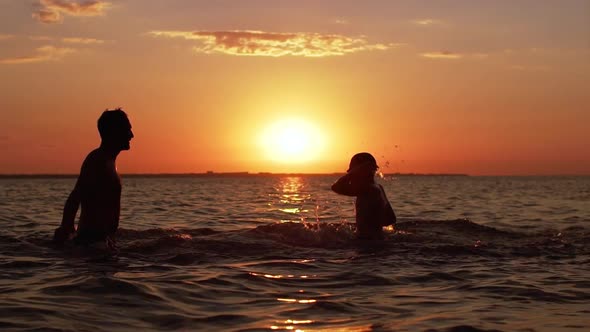 Silhouettes of Adult Father and Little Boy Diving and Swimming in Sea Together During Beautiful