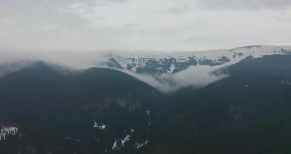 Aerial Top View Over Cloudy Rocky Snowy Mountain with clouds.Italian Alps Mountains with Wild Windy