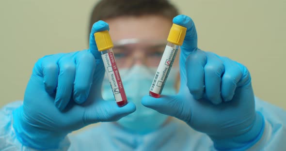 Competent Medical Worker in Protective Uniform Holding Test Tube with Blood for Analysis on COVID 19