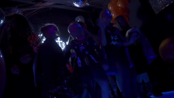 Group of young kids dancing in dark night club. Halloween day party concept.