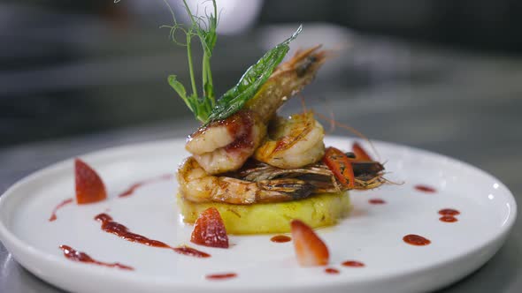 Closeup Delicious Fried Prawns on Pineapple Decorated with Greenery and Chili Sauce on Plate