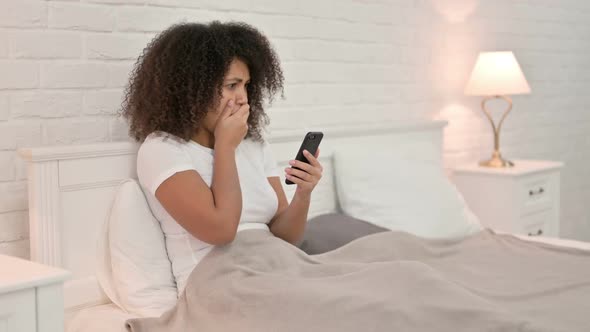 Failure Young African Woman Reacting to Loss on Smartphone in Bed