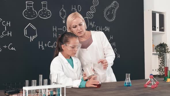 Schoolgirl and Chemistry Teacher Doing Experiment in Classroom