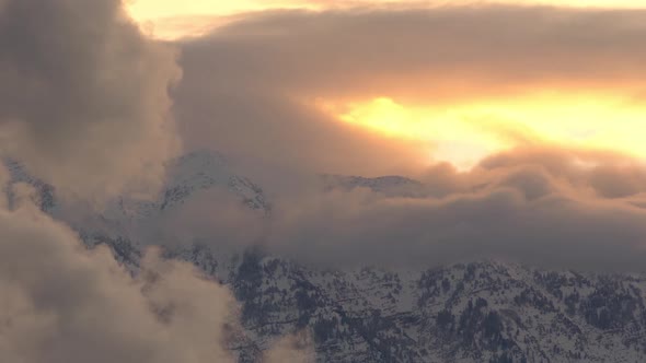 Low foggy clouds moving over snow covered mountains