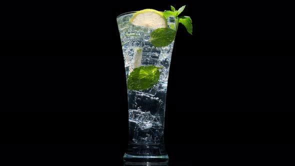 mojito with mint and lime in transparent glass rotating on black background