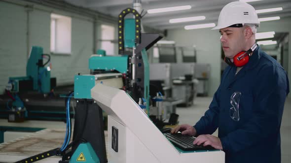 A Factory Worker is Standing at the Control Panel