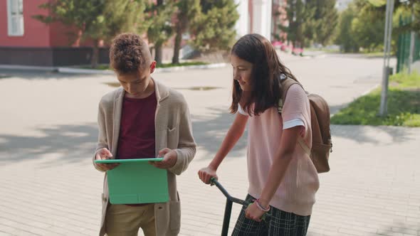 Girl Watching Boy Playing on Tablet Outside