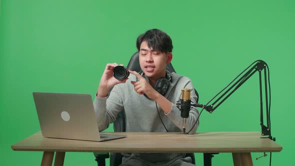Asian Man With Headphone And Computer Reviewing Camera Len On Green Screen Background