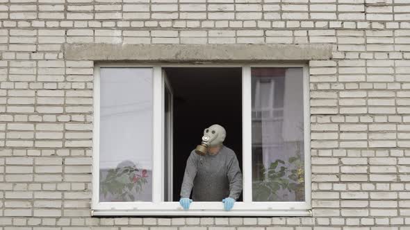 Old Man in Gas Mask Stay at Window Isolated at Home on Quarantine. Coronavirus