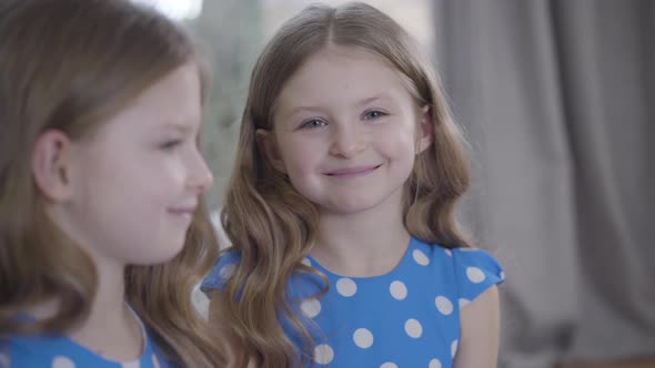 Portrait of Two Identical Twin Sisters with Brunette Hair and Grey Eyes Smiling. Focused at Face of