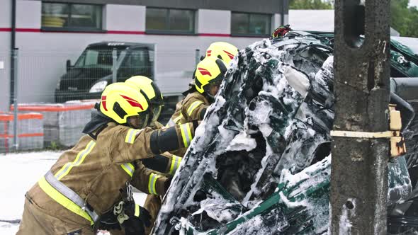 Firefighters Turning the Wrecked Car After Extinguished Fire