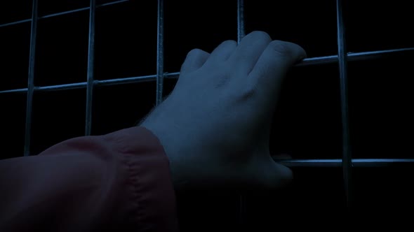 Prisoner Holds Bars In The Dark