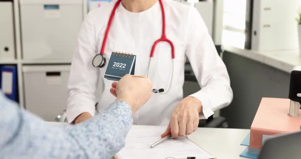 Patient Giving Smiling Doctor Desk Calendar for 2022 at Appointment in Clinic  Movie Slow Motion