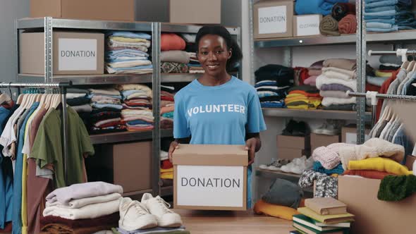 Portrait View of the Multiracial Volunteer Woman Holding Box with Clothes for Donation and Looking