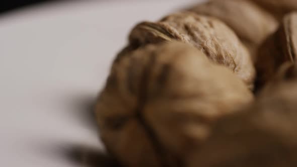 Cinematic, rotating shot of walnuts in their shells on a white surface - WALNUTS 