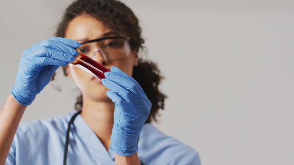 Video of biracial female doctor holding test tube on blue background