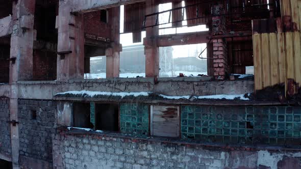 Sun shines through floors of vacant deteriorating industrial building, drone rise up shot