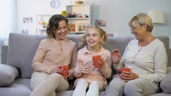 Female Family Members Talking Sitting on Home Sofa With Cups of Tea Together