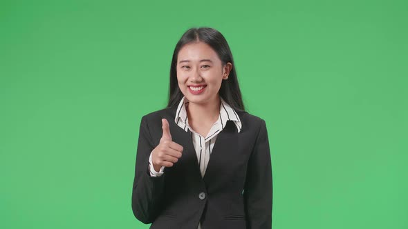 Business Woman Showing Thumbs Up Gesture And Smiling While Standing In The Green Screen Studio