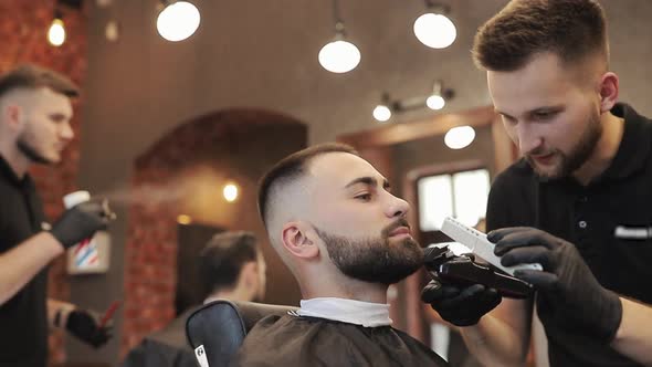 Professional Barber Holding Razor in Hands and Shaving Face of Man