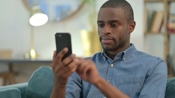 Young African Man Using Smartphone at Home