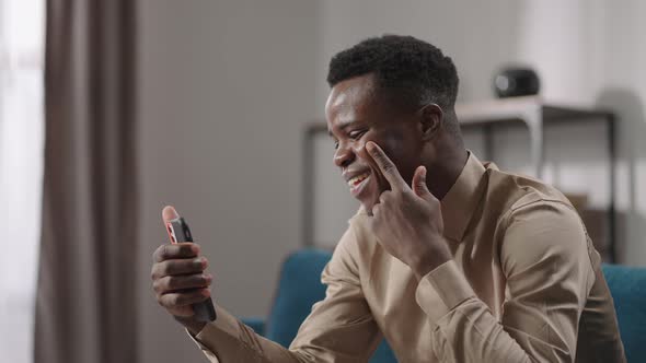 Joyful Young Afroamerican Guy is Chatting By Video Call in Mobile Phone at Home Laughing and Talking