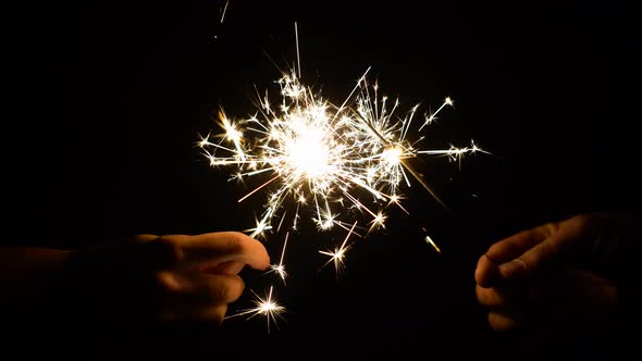 Hands with Burning Sparklers in Darkness 